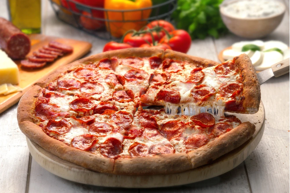 Freshly baked pizza with a slice lifted from the pie