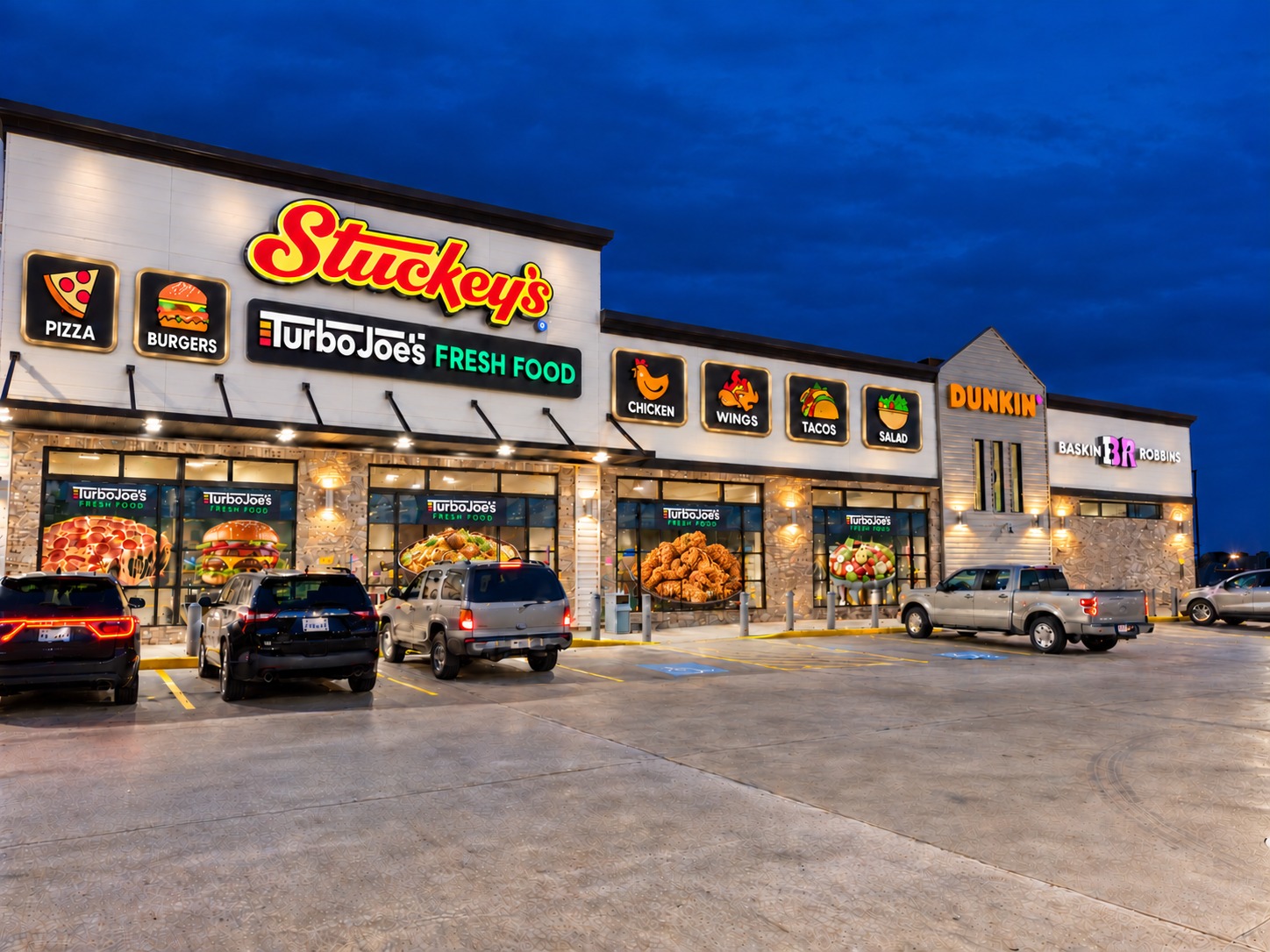 Stuckey’s storefront at night with illuminated Turbo Joe’s signage and food window graphics